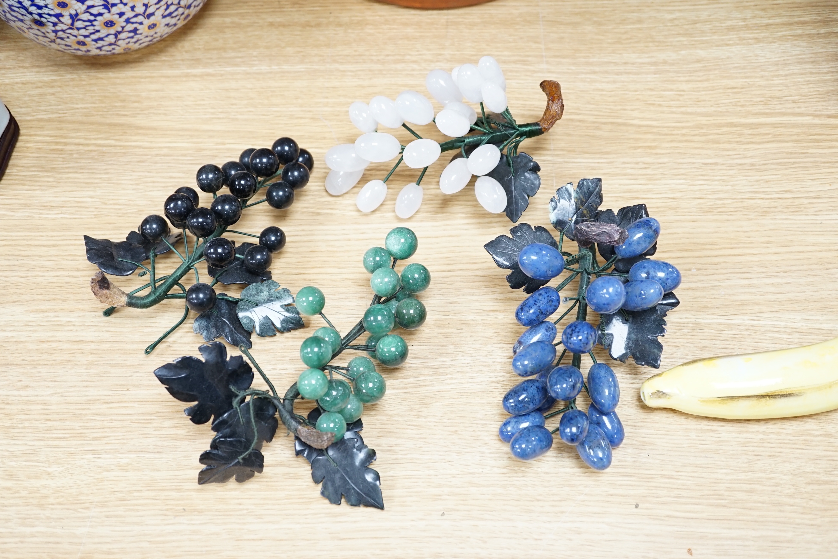 Five polished hardstone and soapstone bunches of grapes and six glazed china fruits, banana 19cm long (11)